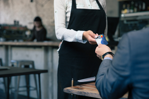 man handing waitress a credit card at a restaurant